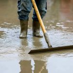Worker smoothing wet concrete floor