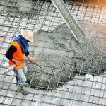 Top view of builders in orange shirt pouring concrete works on the construction site